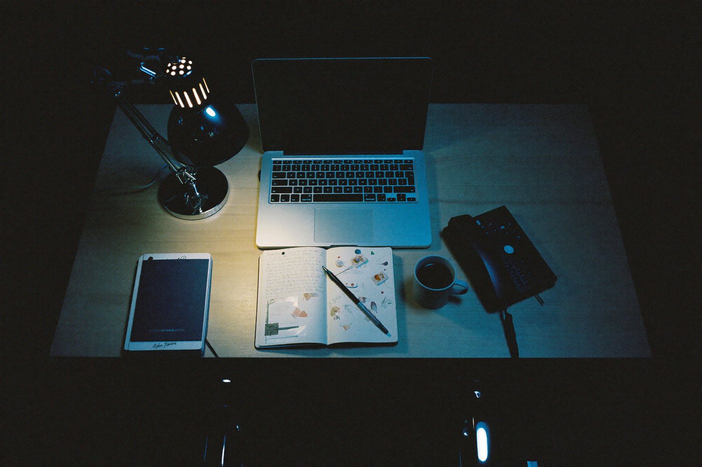 Mesa simples com notebook e caderno à noite
